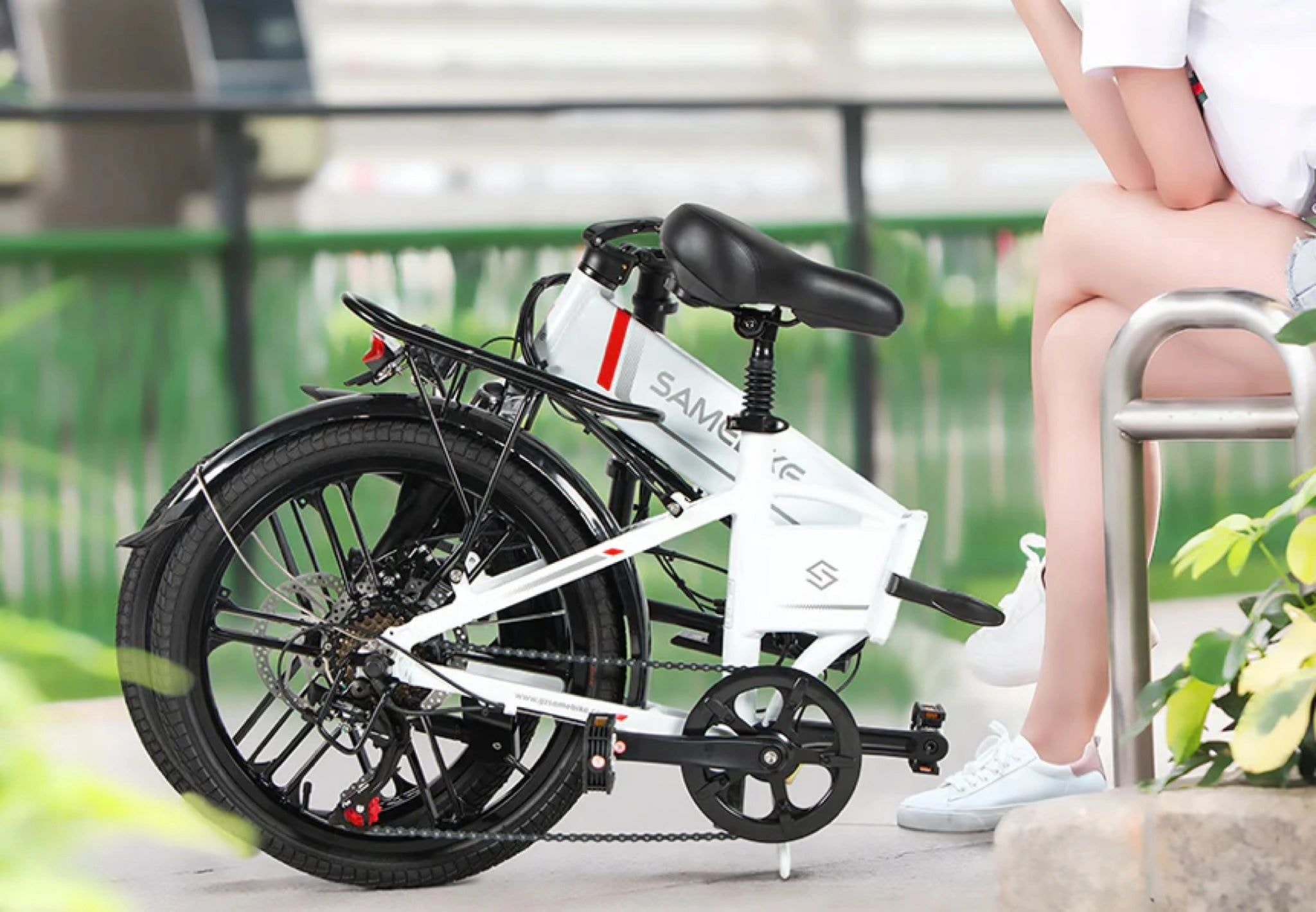 Person holding white folding e-bike outdoors